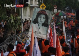 Simpatisan dari Partai Buruh membentangkan poster wajah Marsinah saat berunjuk rasa