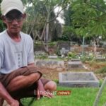 Seorang perawat makam menggunting rumput